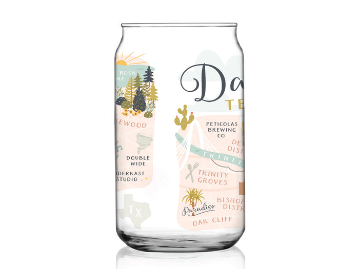 The Dallas Map Can Glass by Onderkast Studio is a clear glass cup featuring a city map illustration of Dallas, Texas with labeled neighborhoods, local landmarks, trees, cacti, and pastel-colored buildings.