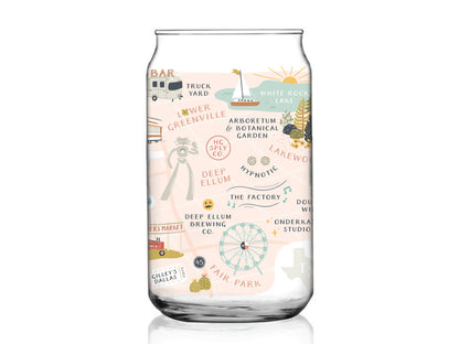 The Dallas Map Can Glass by Onderkast Studio is a clear glass cup featuring a vibrant city map illustration of Dallas, Texas with landmarks like White Rock Lake, Deep Ellum, Lower Greenville, Fair Park, local breweries, and parks.